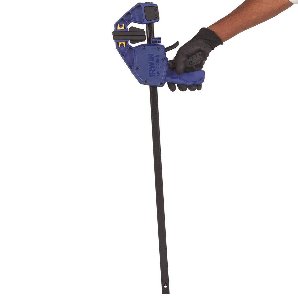 Irwin one-handed bar clamp held by gloved hand, blue head and black bar.