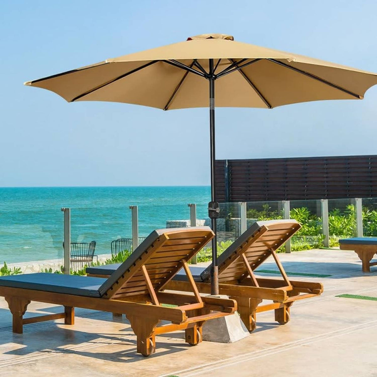 Tan patio umbrella canopy shading wooden loungers near the beach