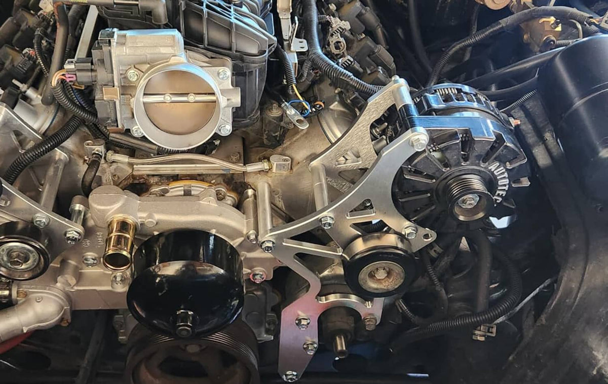 Aluminum serpentine bracket installed in an engine bay with pulleys and belt hardware