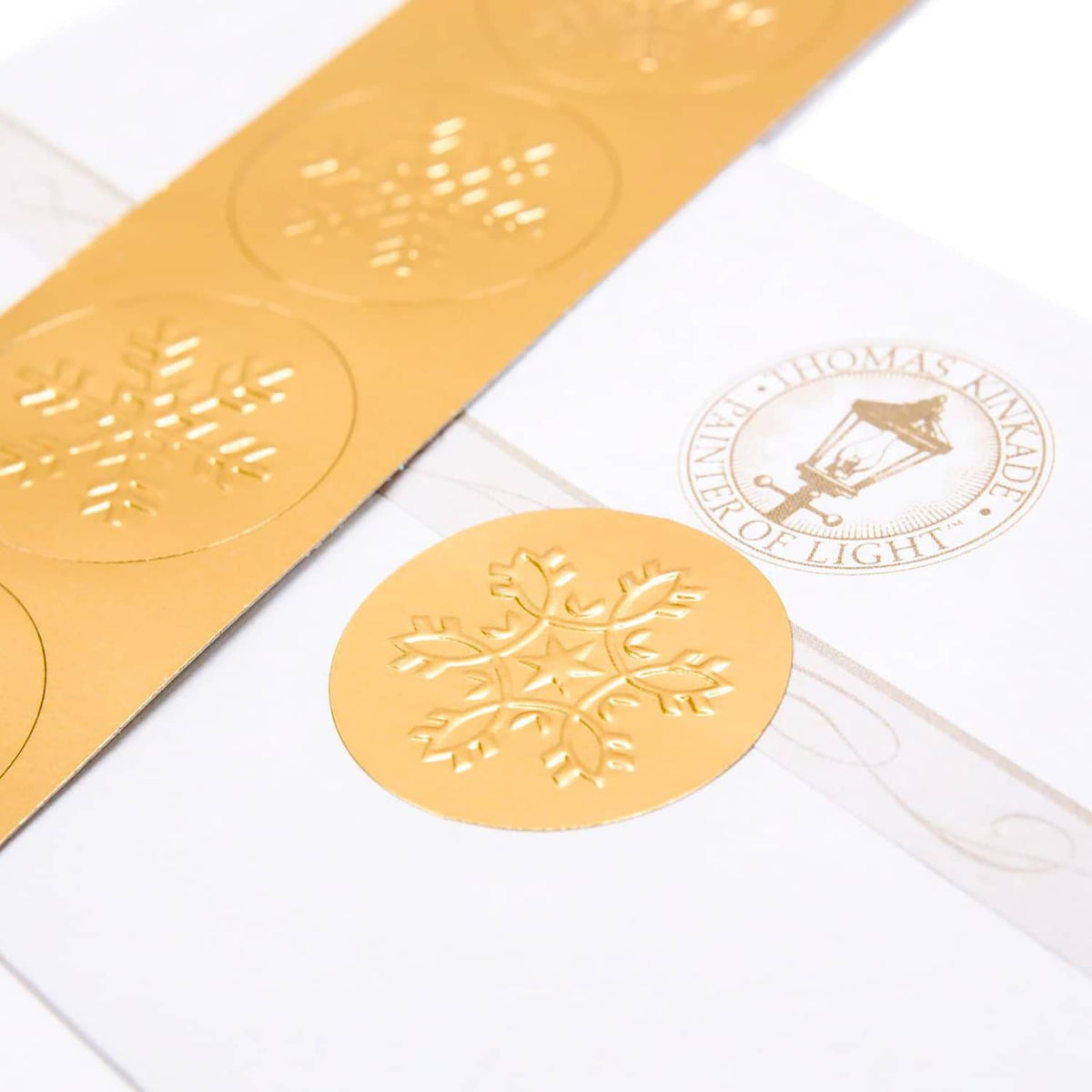 Gold foil holiday seal and Thomas Kinkade logo on Christmas card sheet