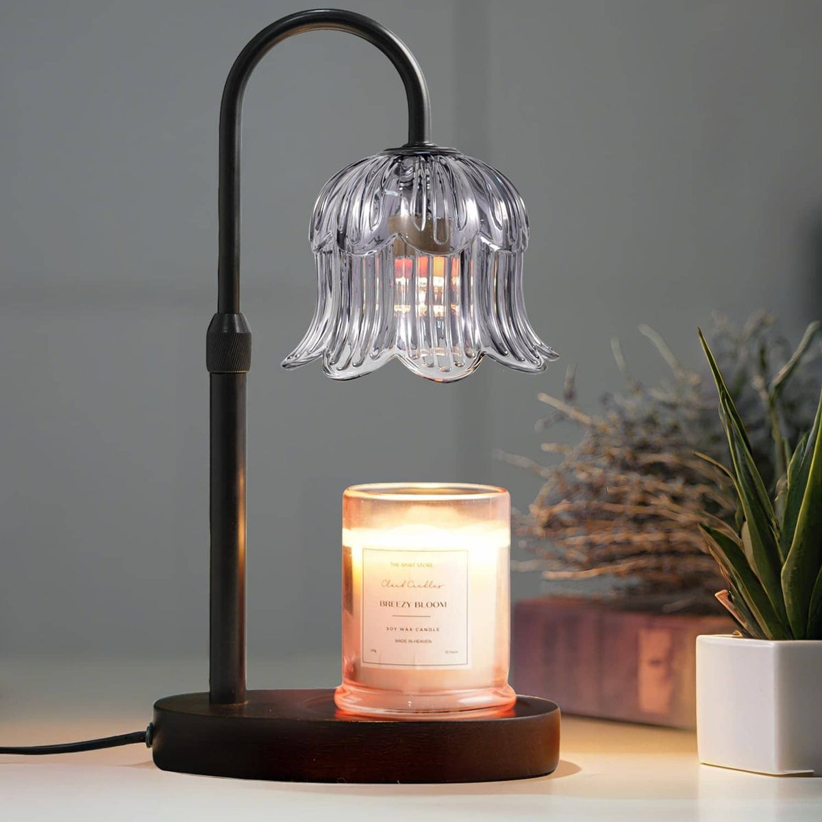 Black candle warmer lamp with ribbed glass shade and glowing candle on round base