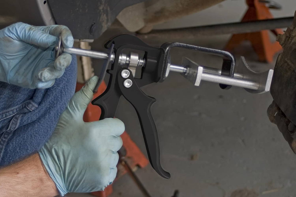 Brake pad spreader tool with gloved hands pressing against brake components
