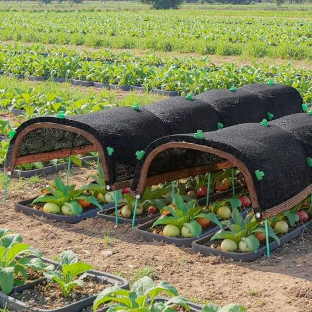 Raised garden bed covered with dark garden shade cloth and hoop supports