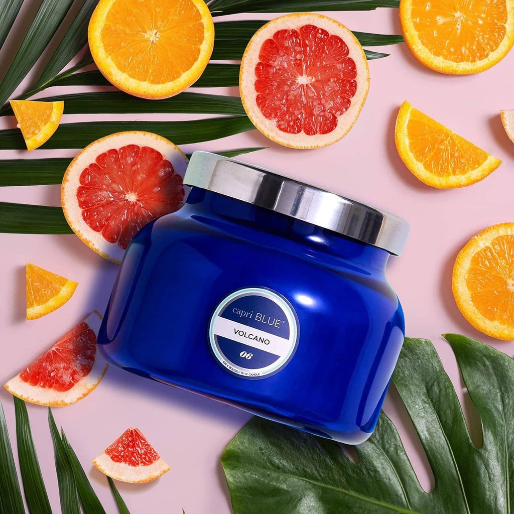 Blue glass jar candle with metal lid, surrounded by orange and grapefruit slices
