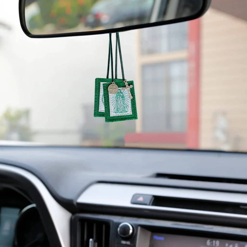 Green scapular charm hanging from rearview mirror, with white panel and round medal