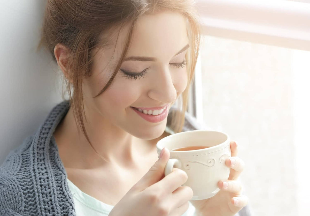 Green tea cup held by a smiling woman