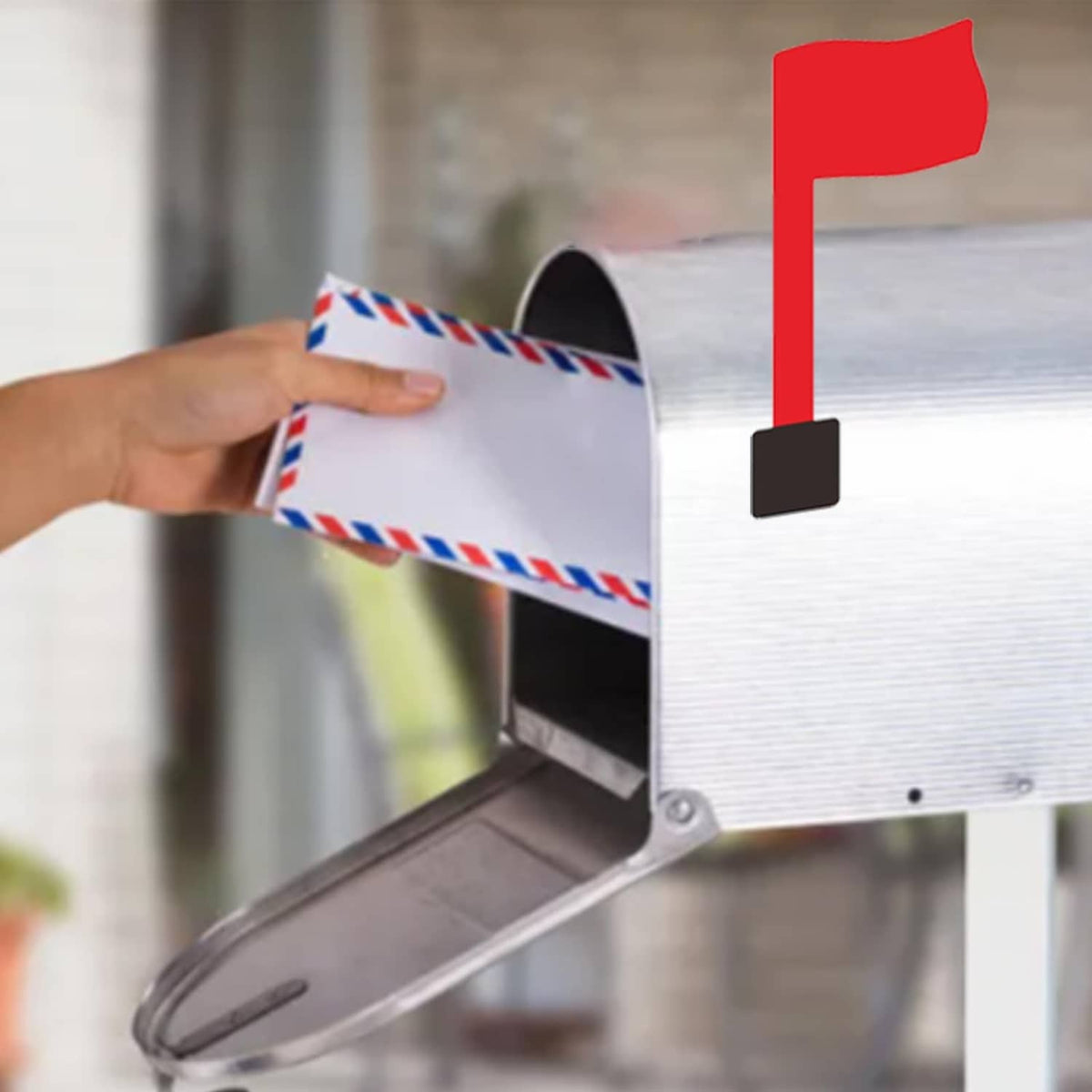 Red mailbox flag kit installed on gray mailbox with hand holding paper