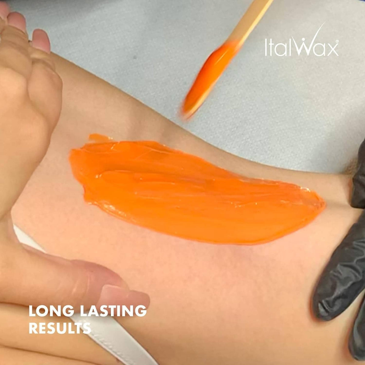 Coral hard wax layer spread on forearm skin, ready for hair removal.