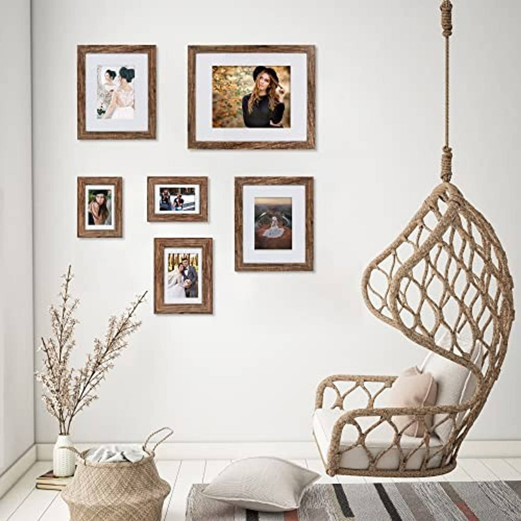 Rustic brown picture frames with glass and white mats arranged on a wall