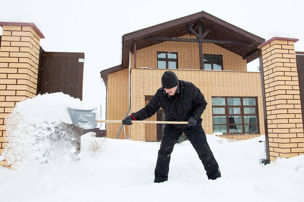 Person shoveling snow in winter with black gloves