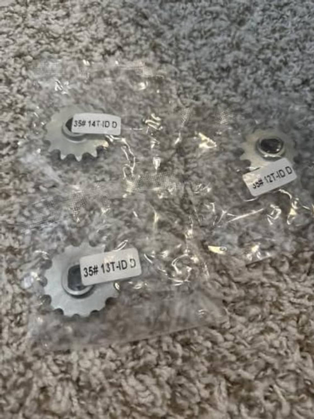 Silver 14T chain sprocket parts on a surface, stamped 35 markings
