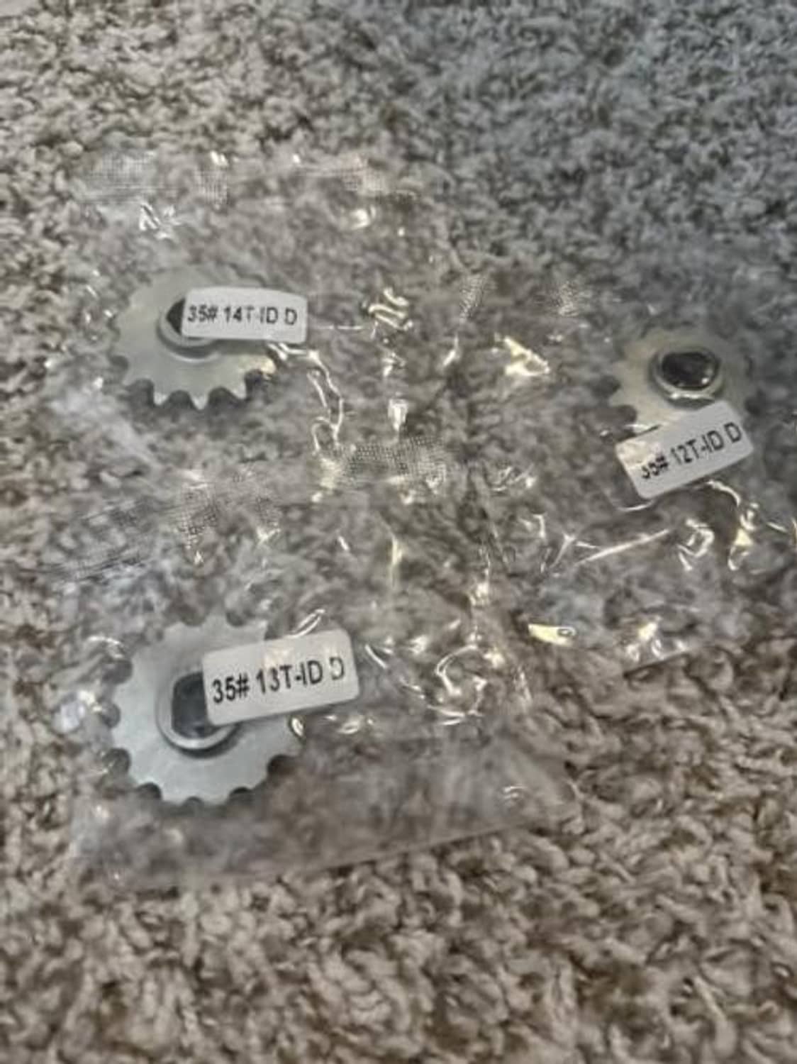 Silver 14T chain sprocket parts on a surface, stamped 35 markings