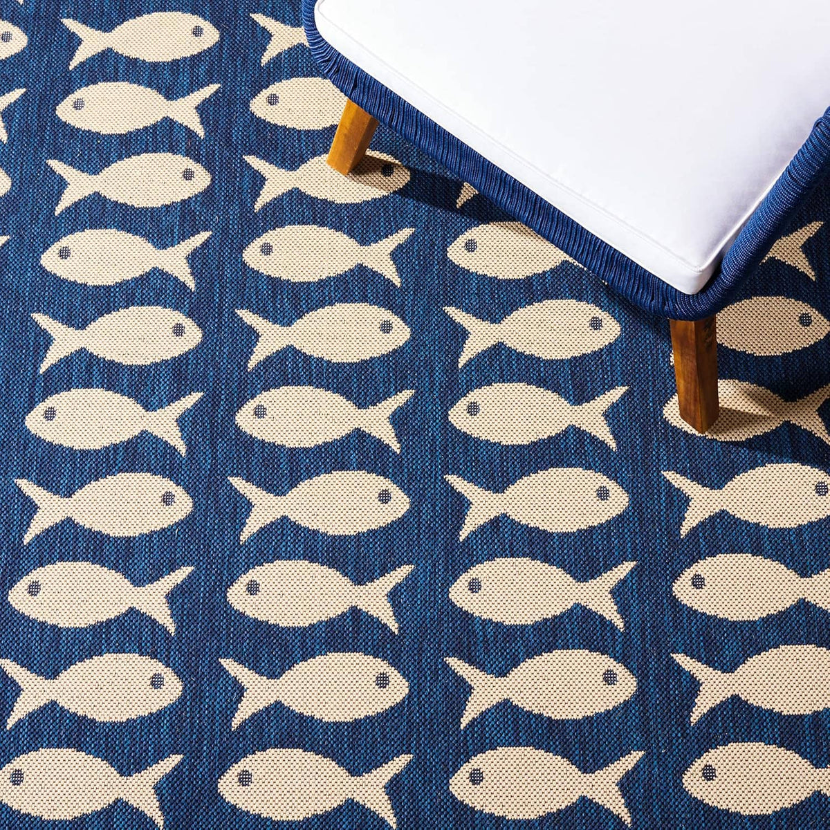Navy outdoor rug with repeating beige fish motif along the border.