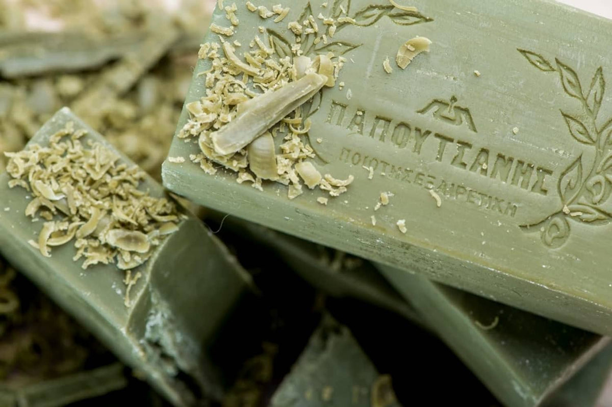 Olive-green bar soap close-up with flakes and embossed text