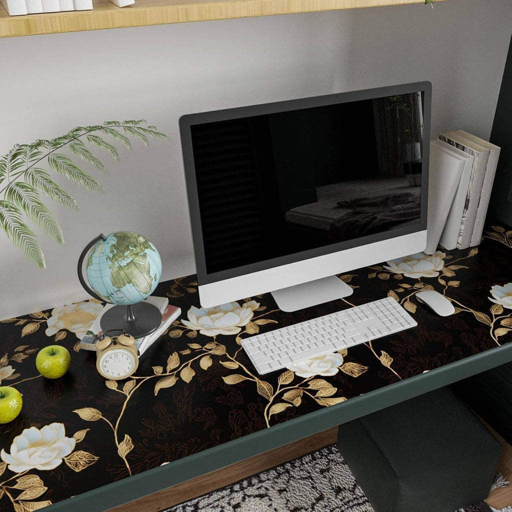 Black floral wallpaper pattern with golden roses and leaves on a desk corner wall