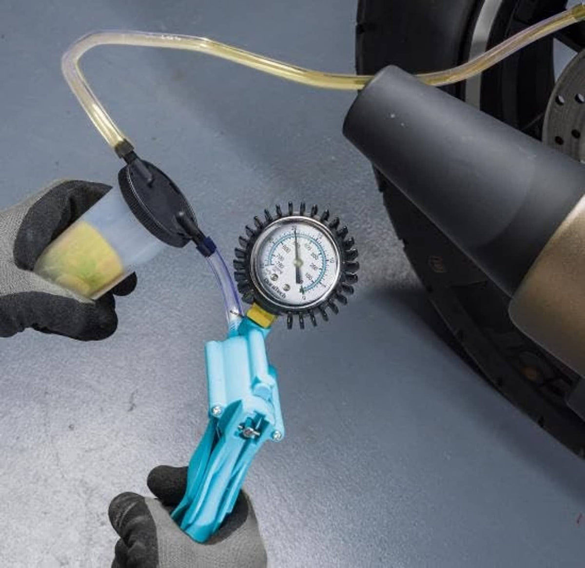 Brake bleeder kit with blue pump, pressure gauge, and clear hose with adapter fittings