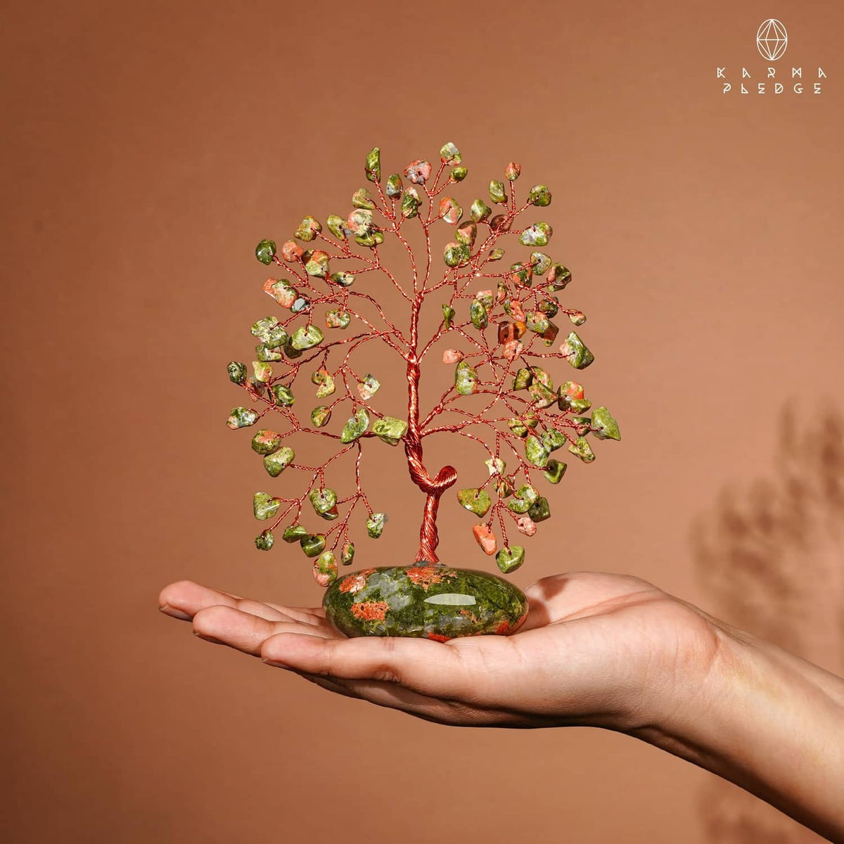 Unakite stone tree in rock base held in hand, green and orange crystal leaves