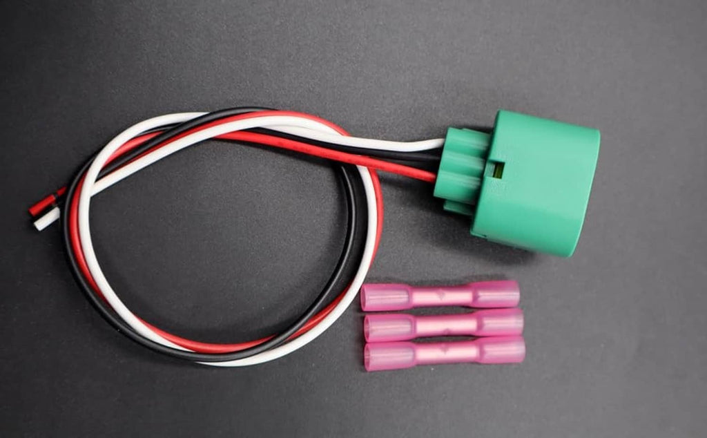 Headlight connector harness with green plug, red/black wires, and pink terminal pieces