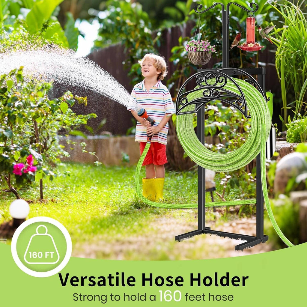 Black hose holder with green coiled hose and spray water stream in garden