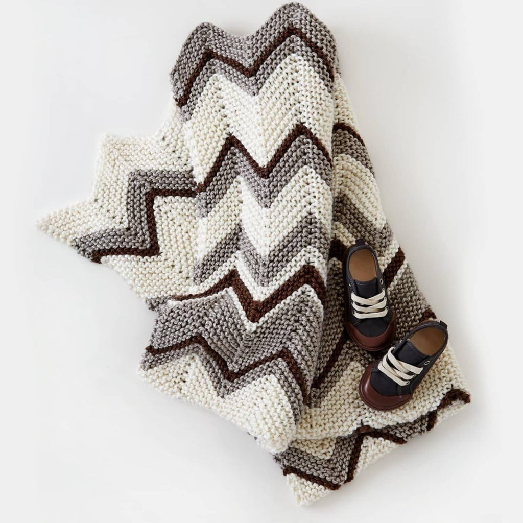 Knitted chevron blanket with cream, gray, and brown stripes