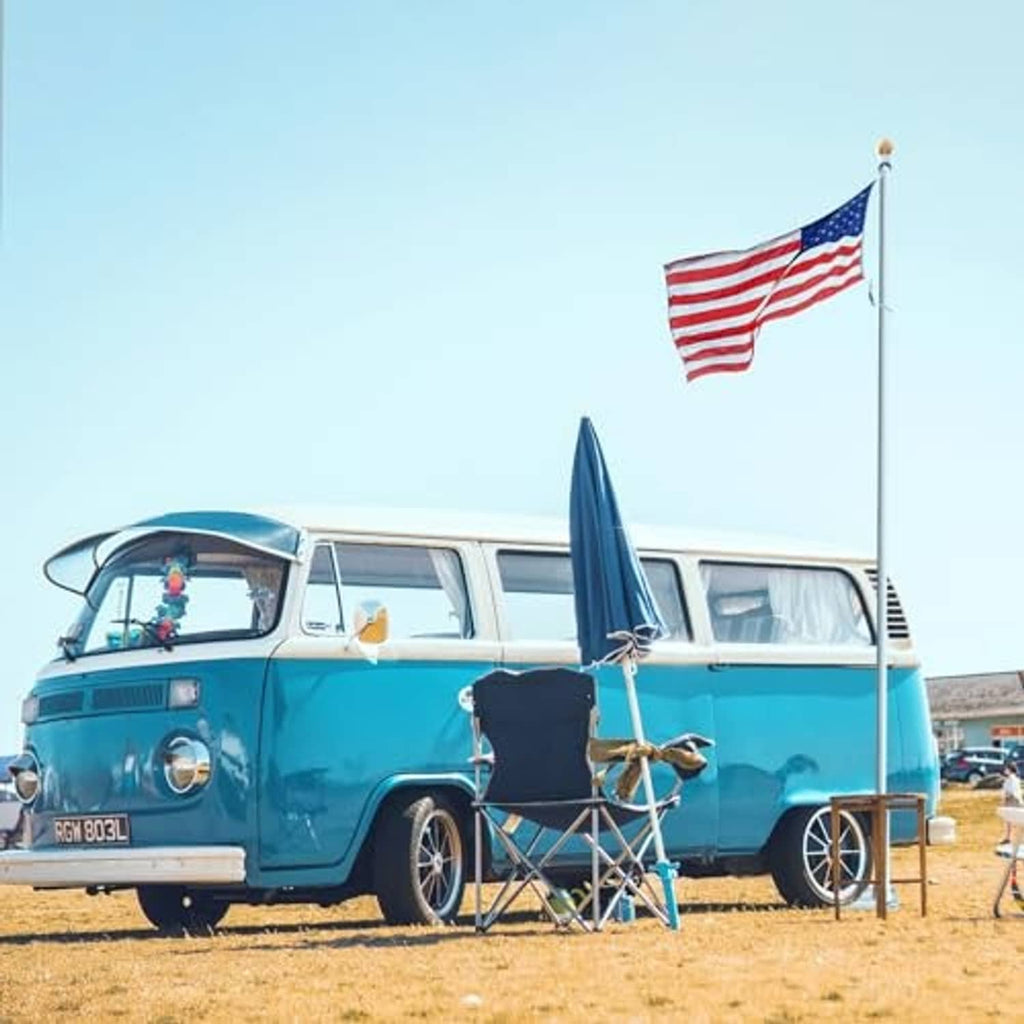Flag pole tire-mount base with flag on upright pole beside classic car