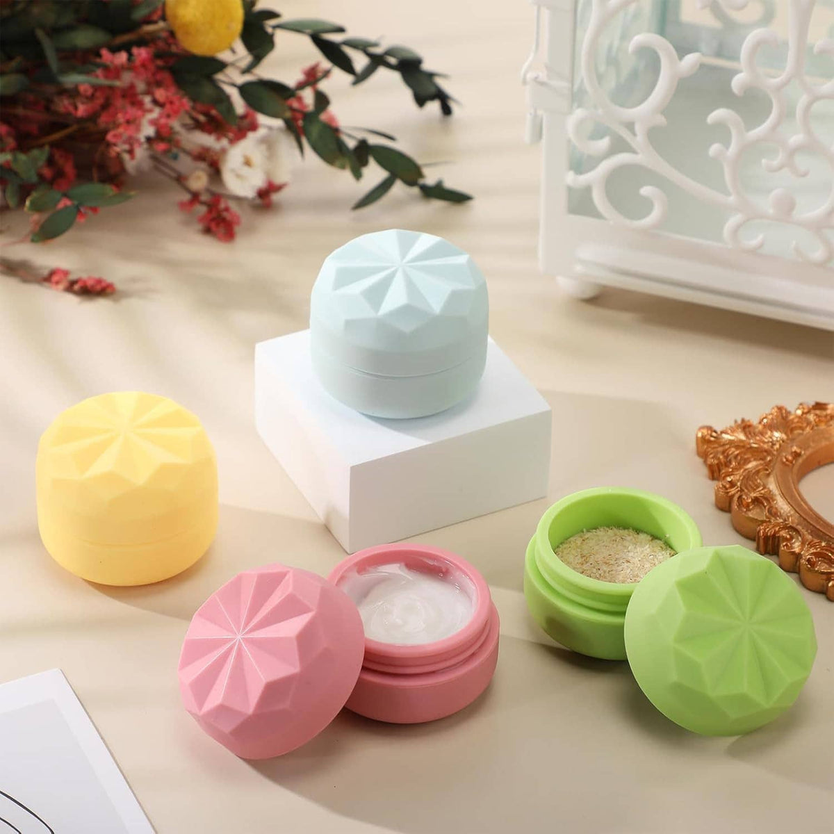 Assorted pastel silicone cream jars with faceted lids in pink, yellow, green, and light blue