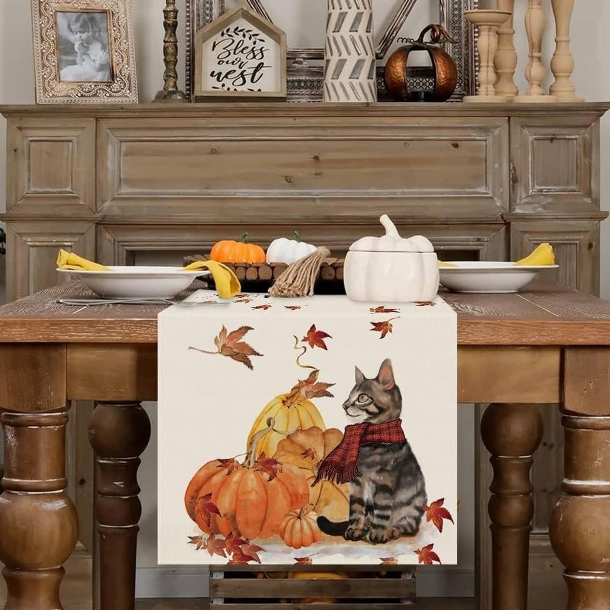 White table runner with cat and pumpkins motif, surrounded by scattered red-brown leaves