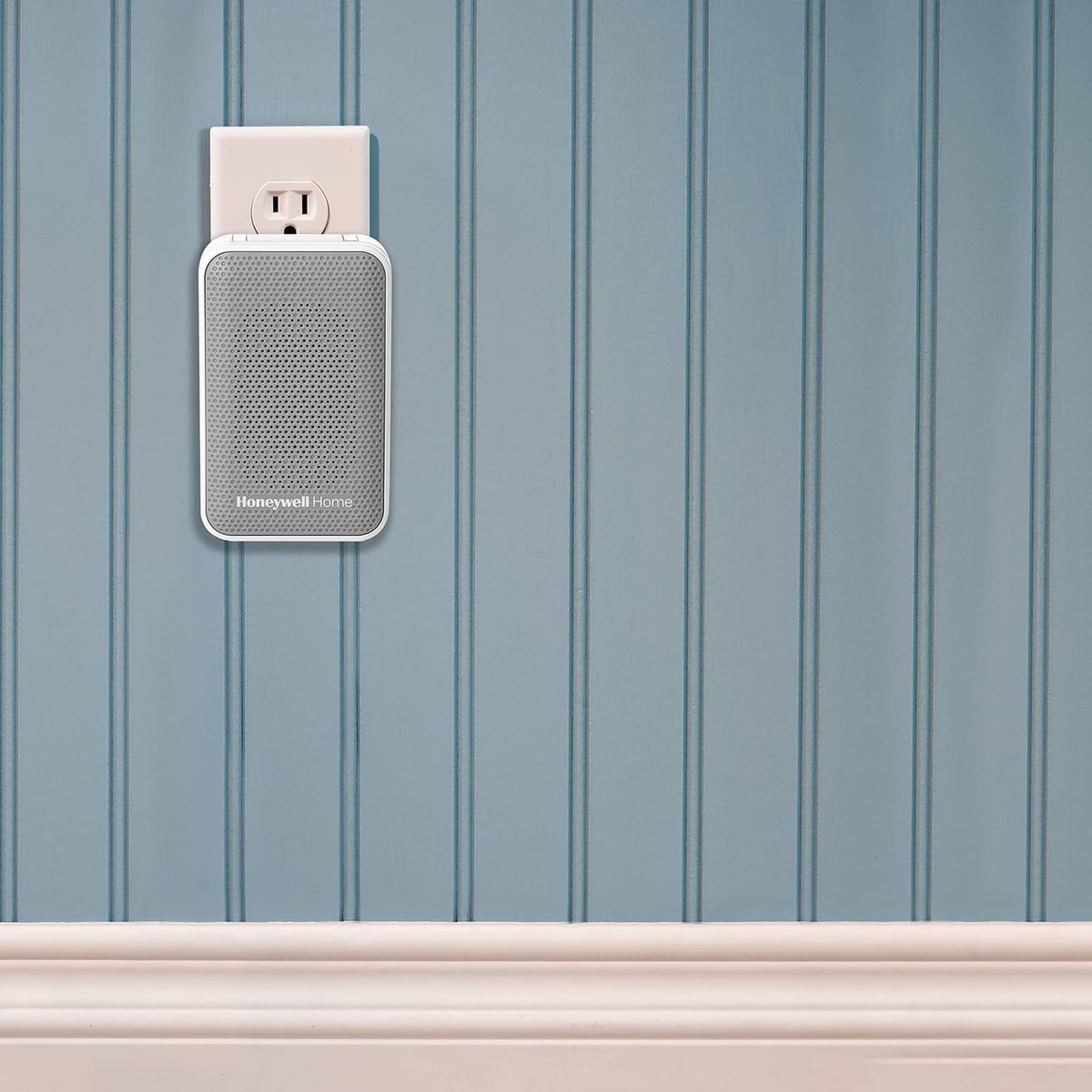 White wireless doorbell chime plugged into outlet on blue vertical panel wall