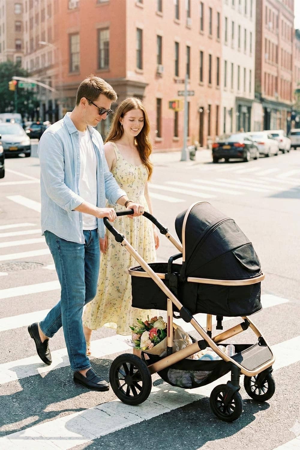Black newborn pram stroller with gold frame, bassinet attached and wheels visible