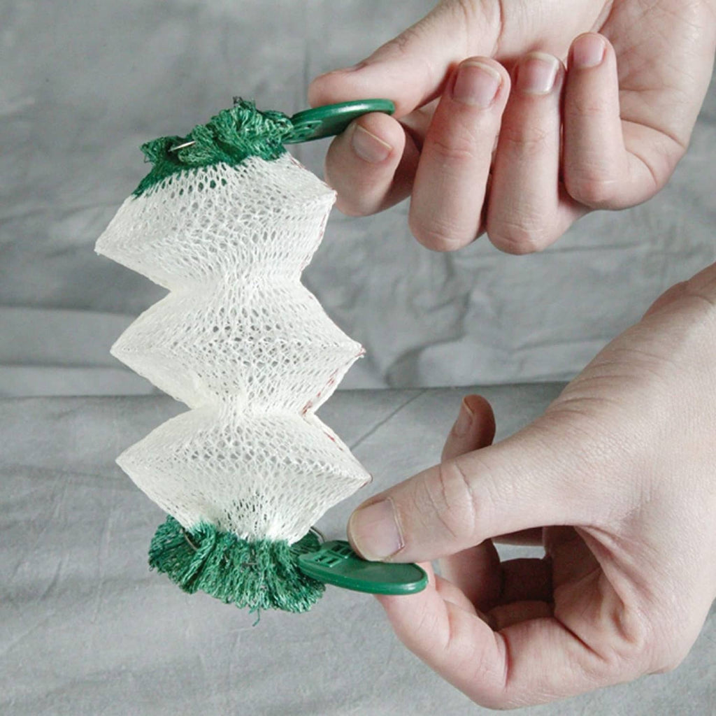 Hand holding green-and-white wick accessory over Coleman Northstar lantern burner