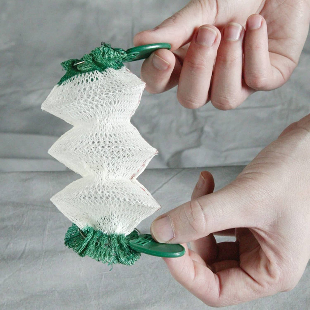 Hand holding green-and-white wick accessory over Coleman Northstar lantern burner