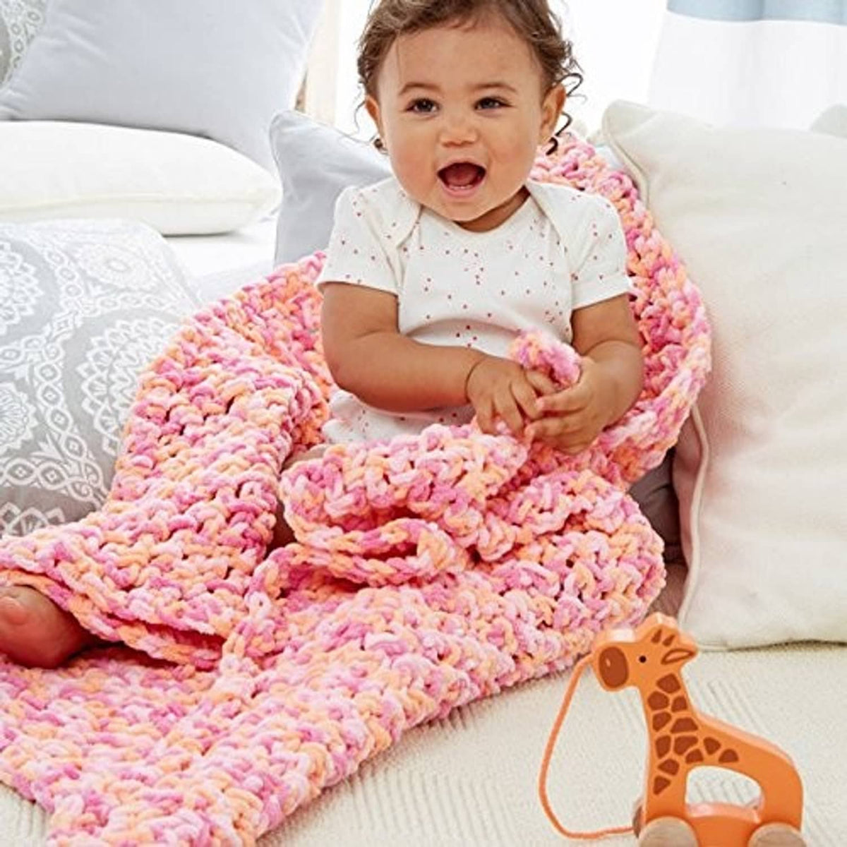 Chunky chenille baby blanket with multicolor loops, shown on a sofa