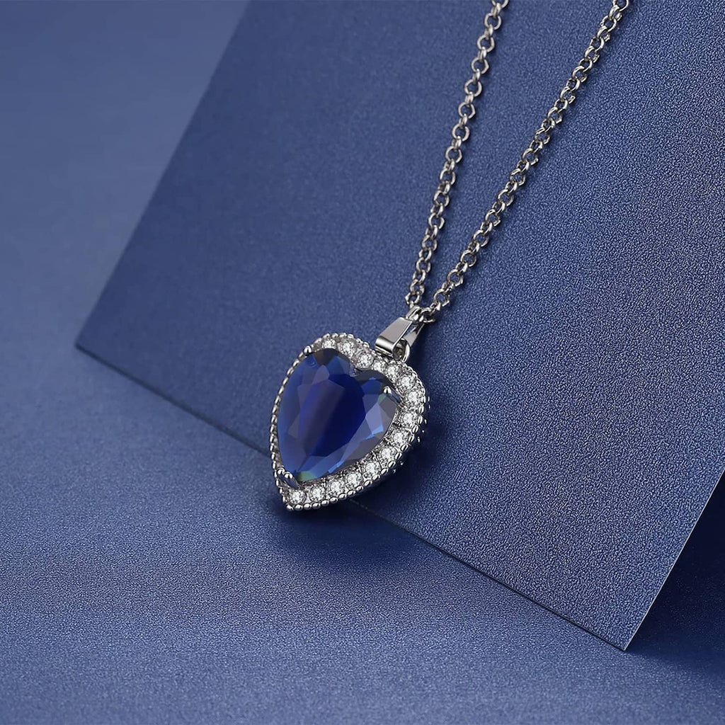Blue heart pendant necklace on chain, shown resting on a blue surface