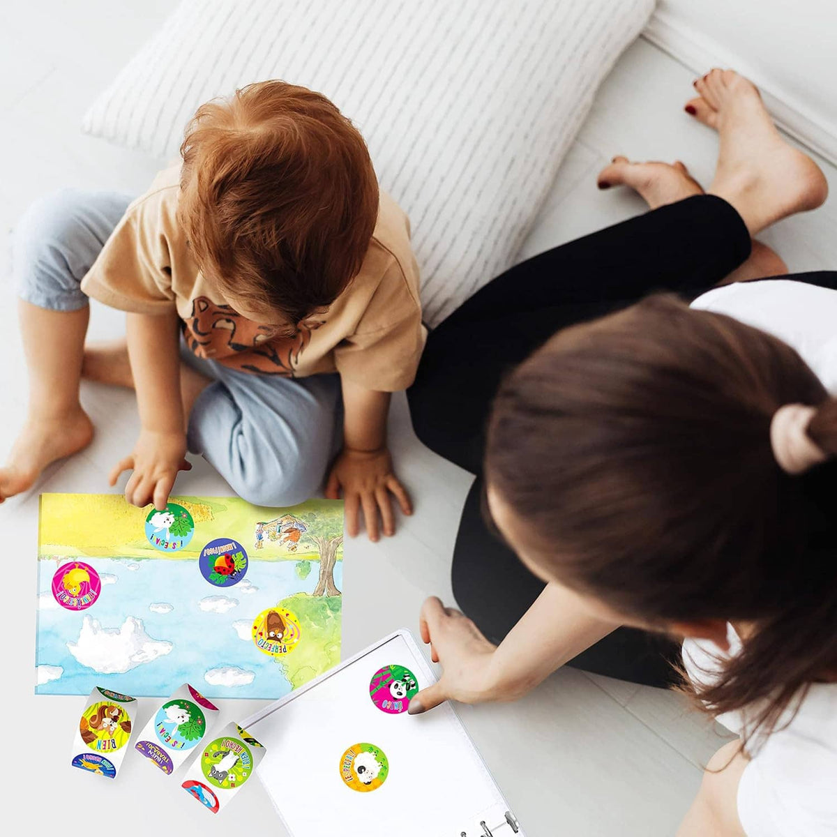 Kids using a sticker sheet and round reward stickers on a living room floor