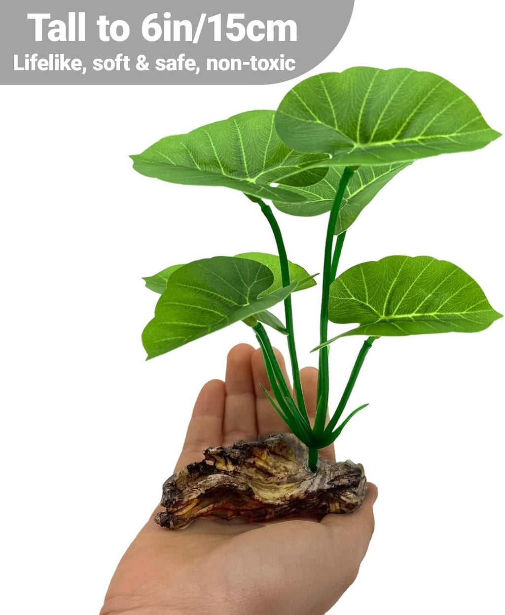 Artificial aquarium plant with green leaves on brown driftwood base, held by hand
