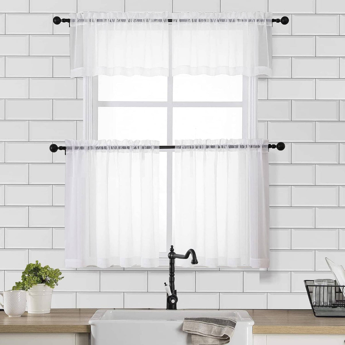 Sheer white window curtain set with ruffled top, hanging on a black rod
