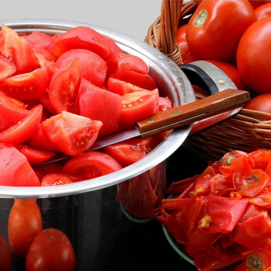 Chopped peeled tomatoes in metal bowl with sliced pieces nearby