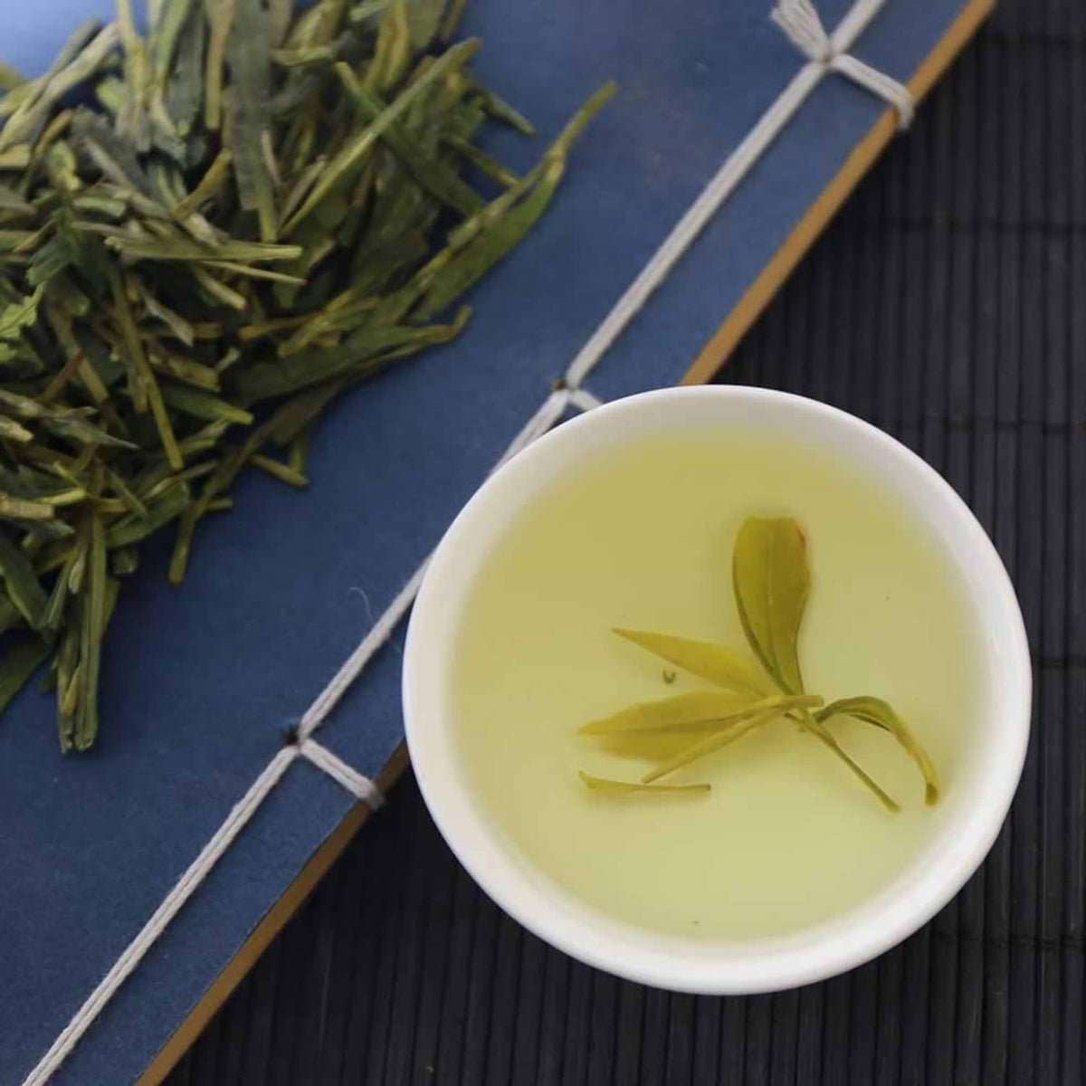 Light green tea in cup with a few floating leaf pieces