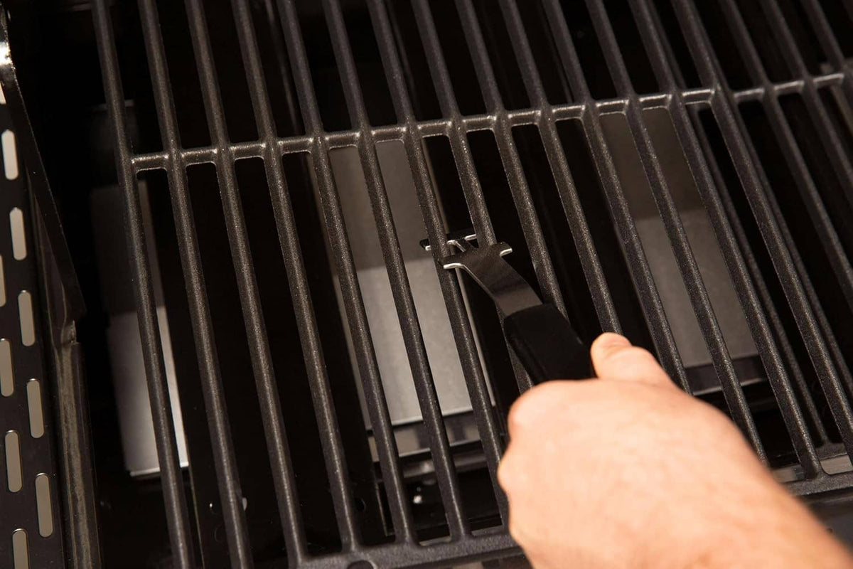 Hand using grid lifter fork to lift grill grate bars