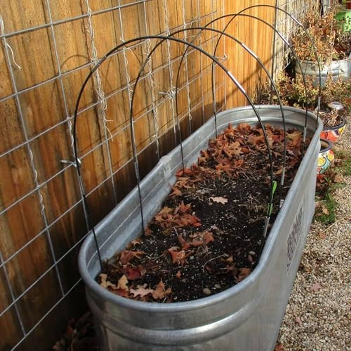 Black garden hoop arches over a raised planter bed