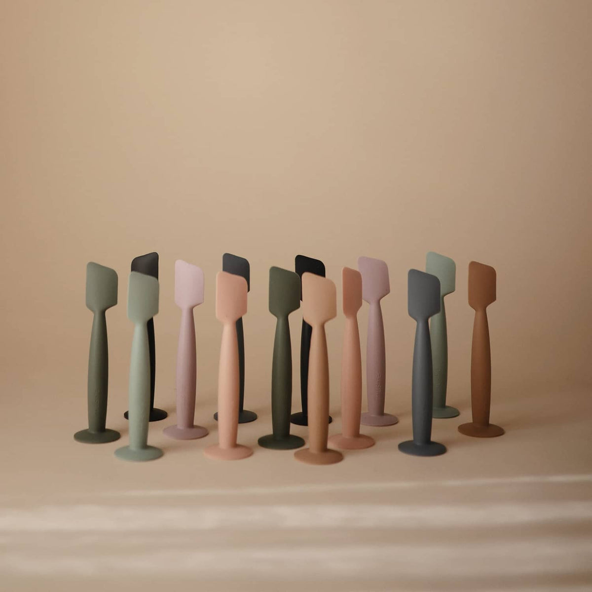 Row of Mushie soft silicone diaper cream applicators in multiple colors