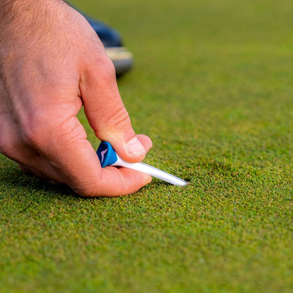 Hand inserting a white plastic golf tee with blue sleeve into the grass