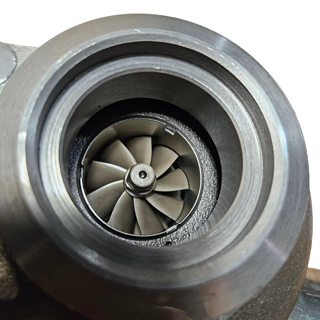 Turbocharger turbine wheel inside silver housing, close-up of compressor inlet