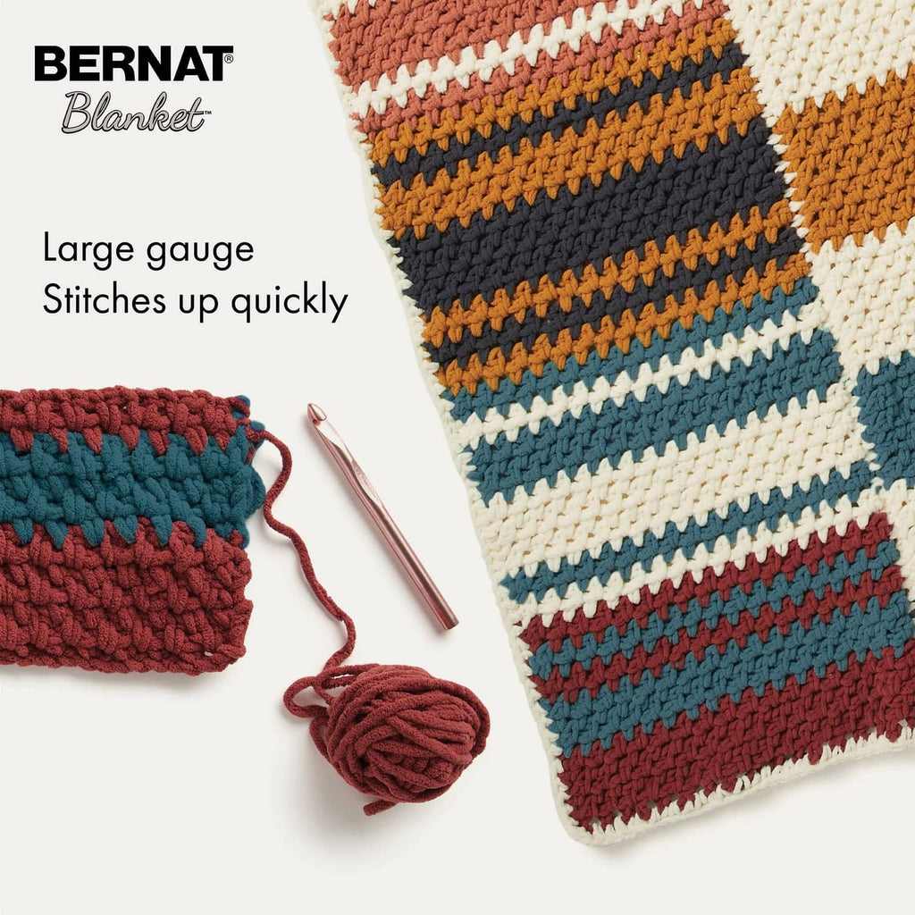 Striped crocheted blanket corner with yarn skein and wound yarn ball.