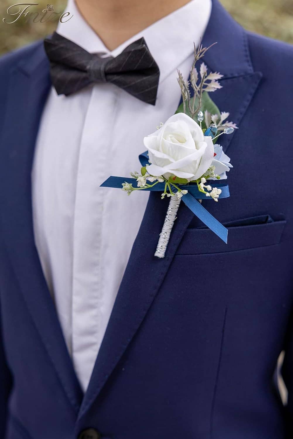 Blue rose boutonniere on a navy suit lapel with white flower accents and ribbon