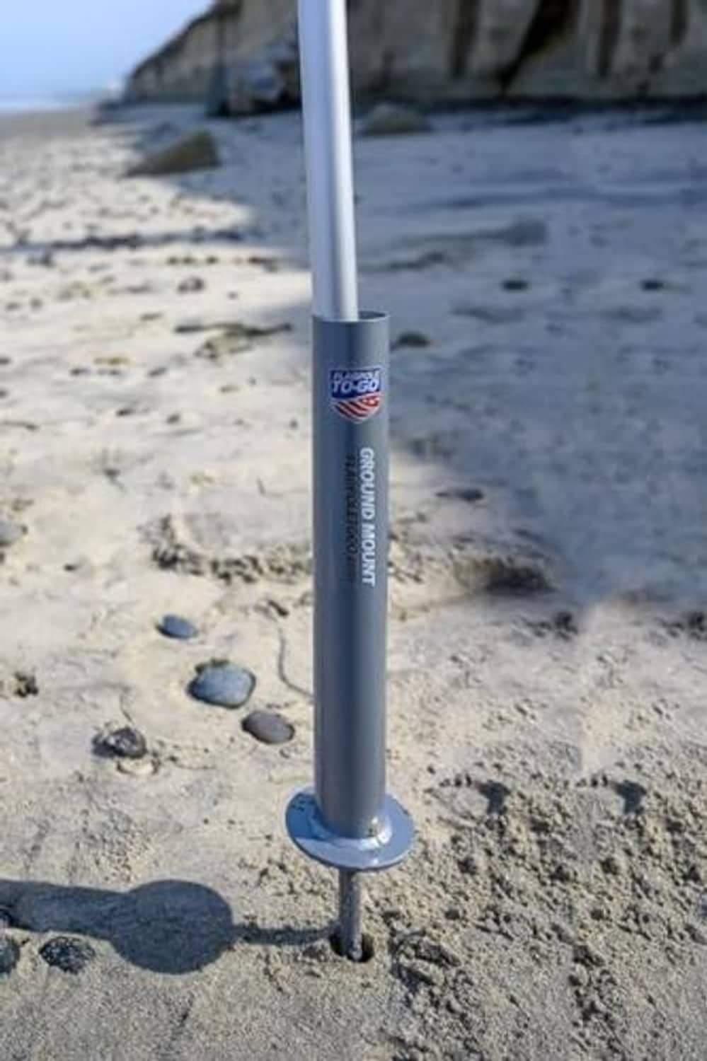 Ground flagpole mount planted in sand with round base plate