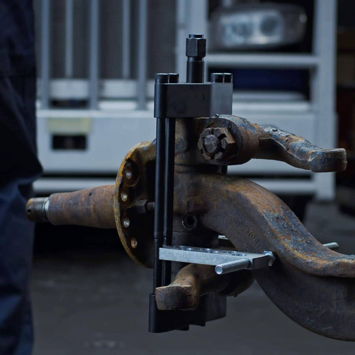 Heavy duty king pin press tool installed on a rusty axle and steering knuckle