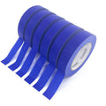 Blue masking tape roll with several loose strips extending outward.