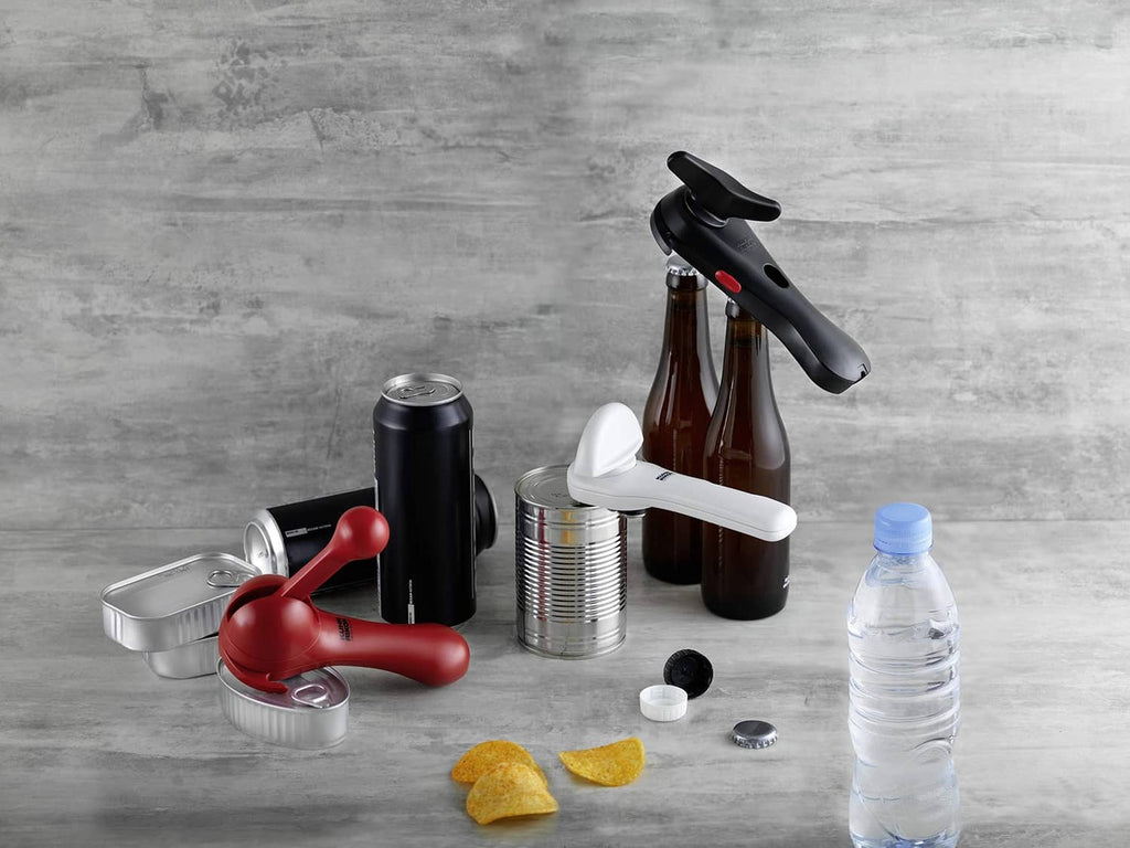 White jar and bottle opener tool with black gripping pads, shown with kitchen accessories