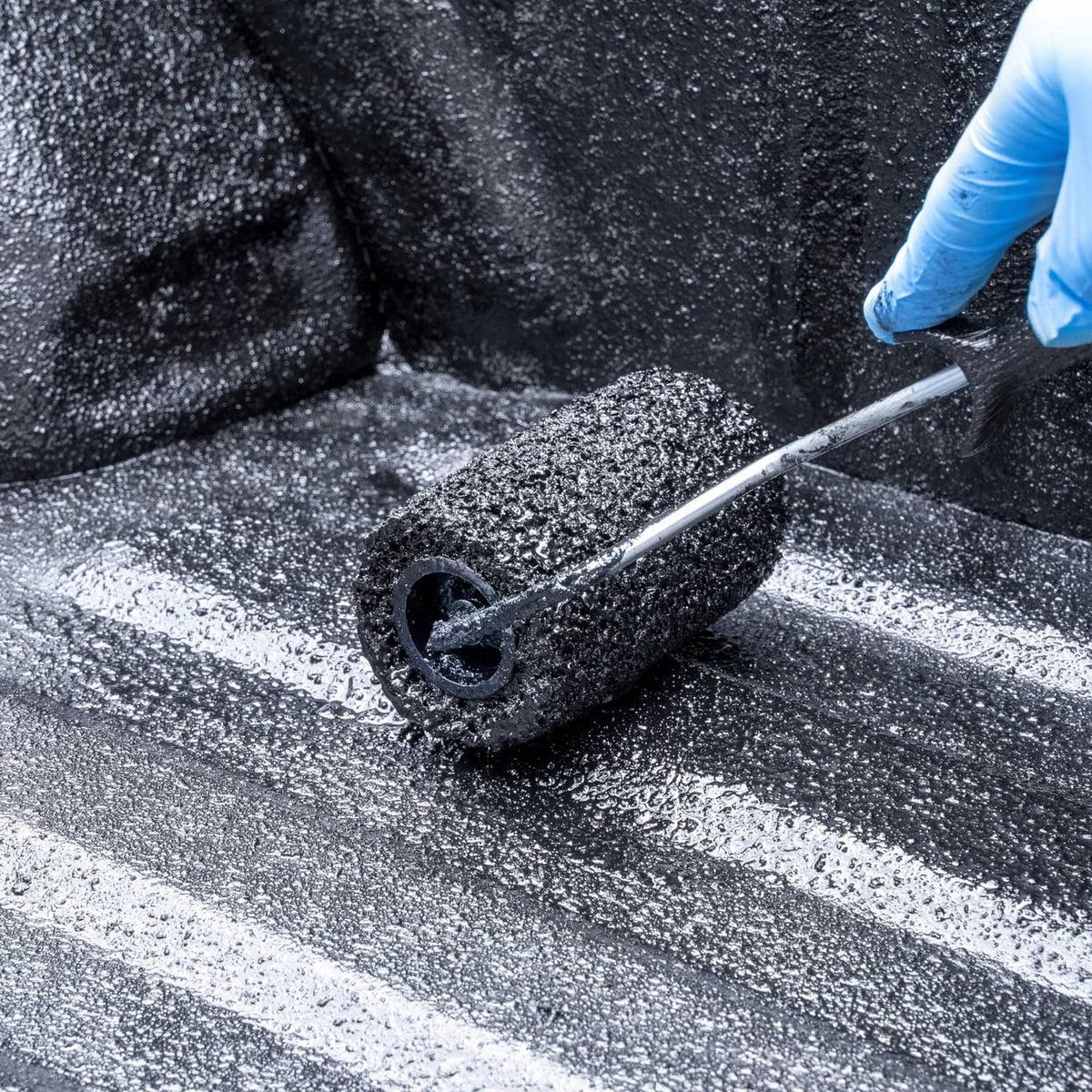 Black textured bed liner coating being rolled onto a truck surface